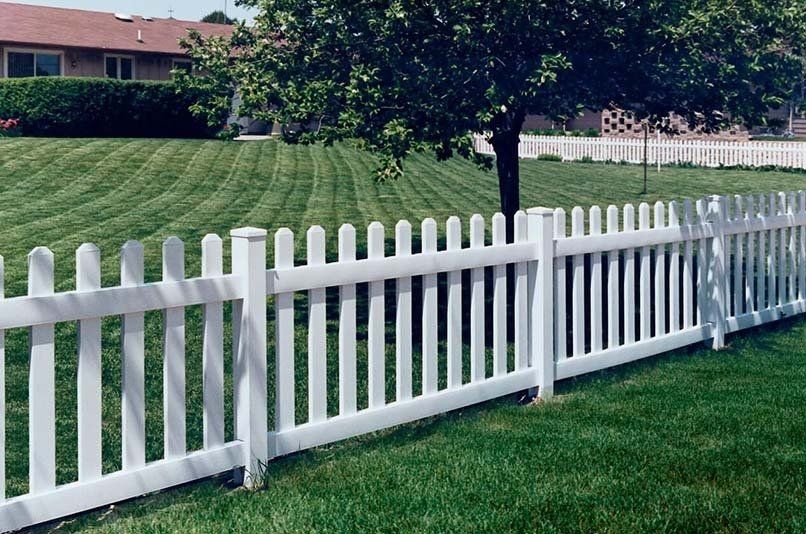 A white picket fence surrounds a lush green yard