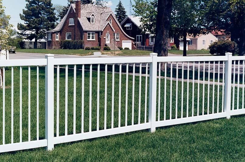 A white fence with a brick house in the background