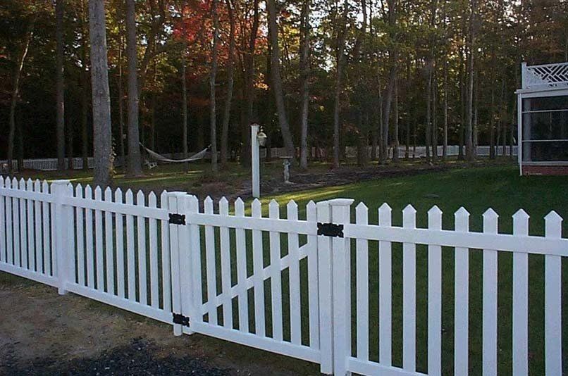 A white picket fence surrounds a lush green yard