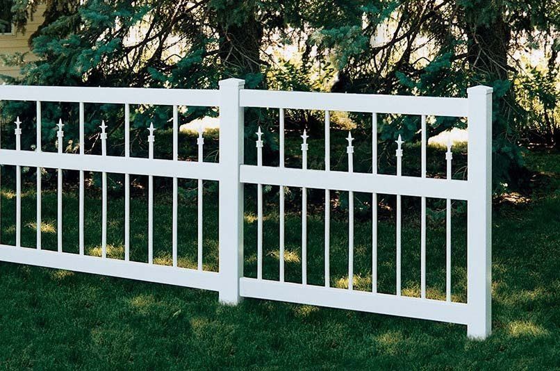 A white fence is sitting on top of a lush green lawn.