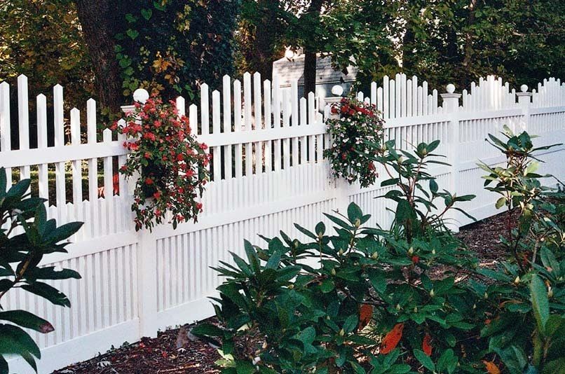 A white picket fence with flowers growing on it