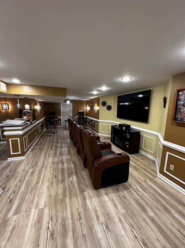 Spacious lounge bar with brown leather chairs, wood floors, and a large wall-mounted TV