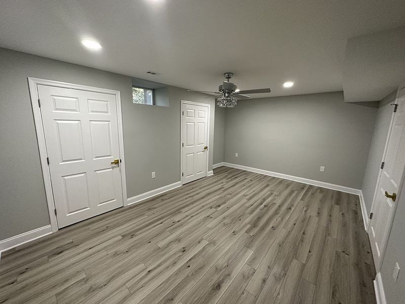 Gray-painted room with white doors, recessed lights, and wood-look flooring; a ceiling fan is visible.