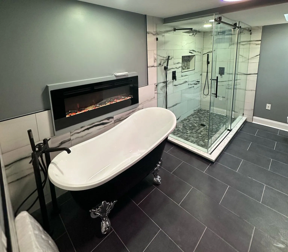 Modern bathroom with a clawfoot tub, glass shower, fireplace, and gray and black tiles.