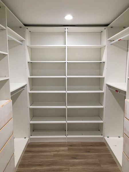Empty white closet with multiple shelves and light wood flooring.