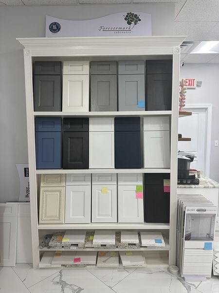 Display of cabinet door samples in various colors, arranged on a white shelf.