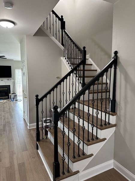 Staircase with black banisters and brown treads ascending to the upper floor, viewed from the entryway.