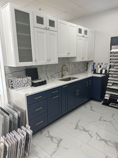 Blue and white kitchen cabinets with a white countertop and gold fixtures.