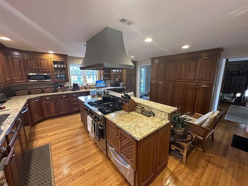 Spacious kitchen with wood cabinets, island, stainless steel range, and granite countertops.