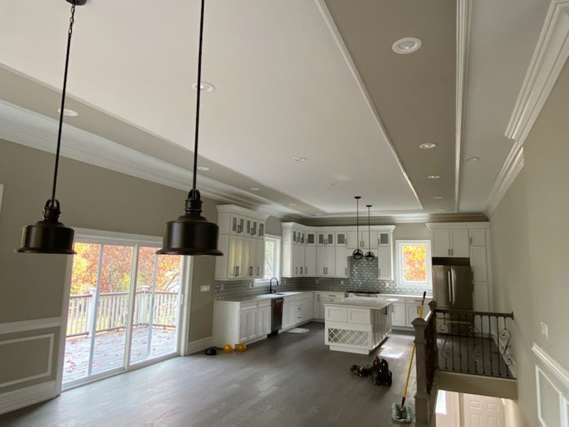 Modern kitchen with white cabinets, dark pendant lights, and a sliding glass door.