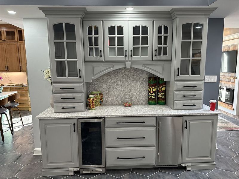 Gray built-in kitchen cabinetry with glass-fronted cabinets, a countertop, and appliances.
