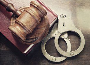 Learn More About Criminal Defense Gavel and handcuffs with red legal book on wooden table