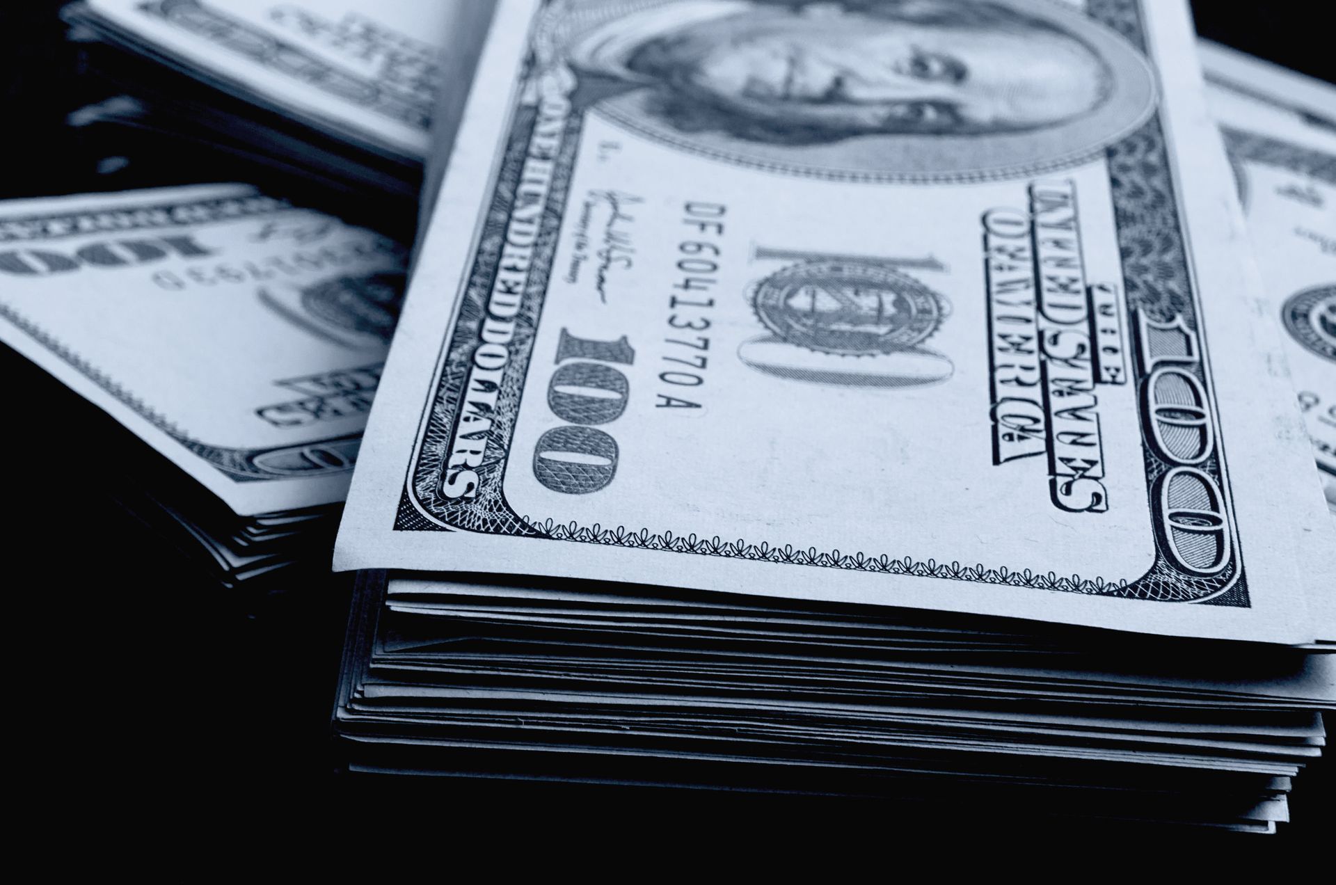 Stacks of US hundred dollar bills, close up on a dark background.