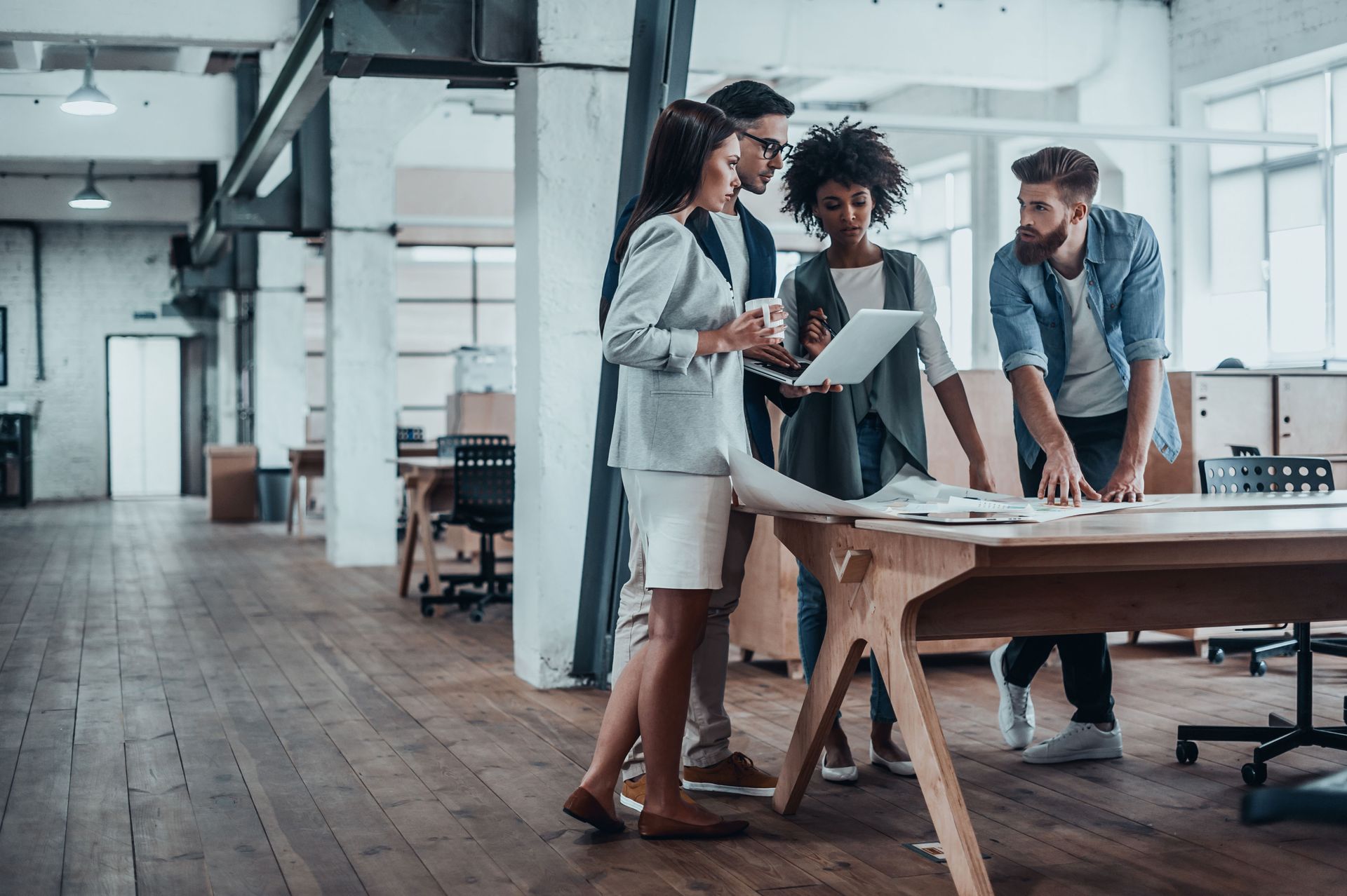 Business colleagues collaborating at a table in a modern office space, reviewing papers.