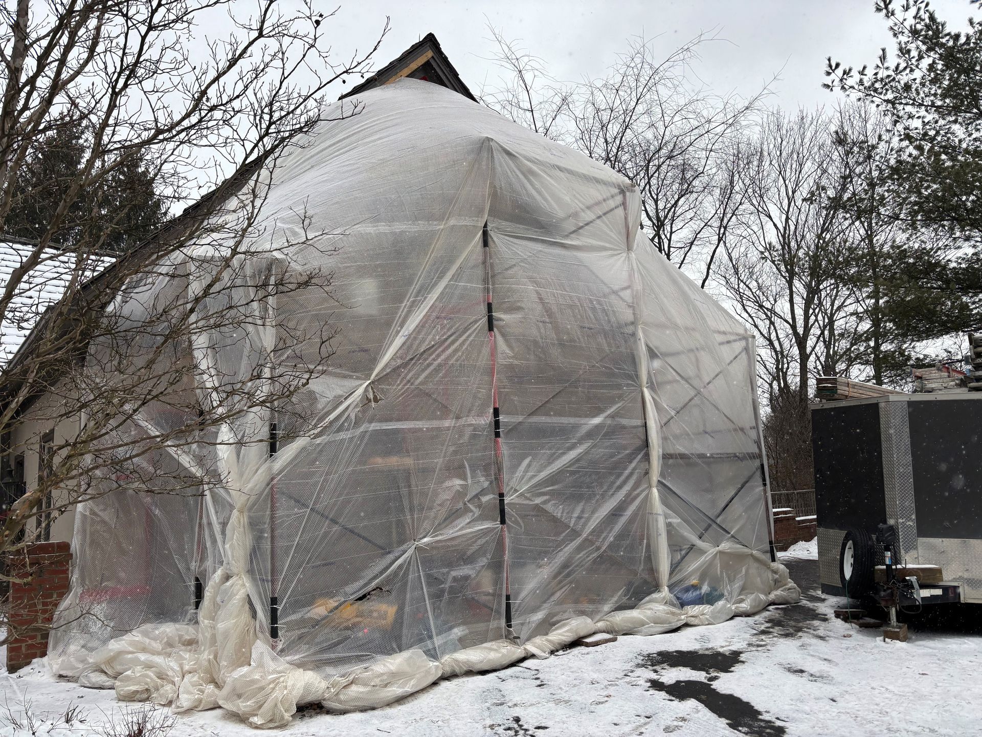 Modern two-story house with white siding, black trim, and gray stone accents. Concrete driveway, green lawn.
