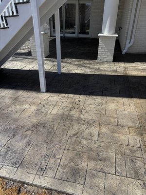 Stamped concrete patio under white stairs and columns.