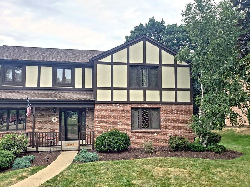 Two-story brick townhouse with brown trim and a small front yard with a pathway.