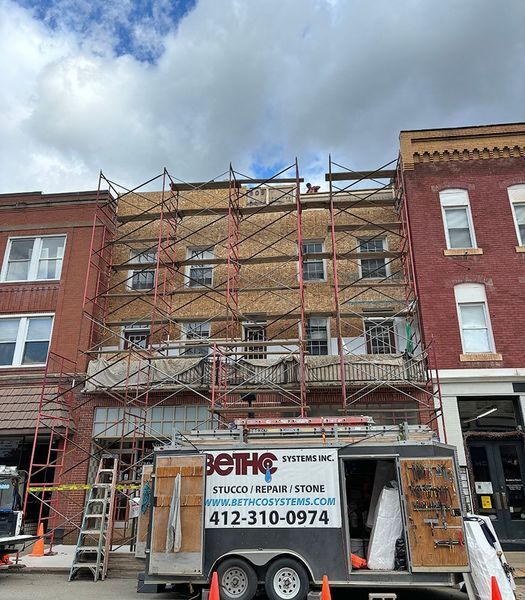Scaffolding on a building with facade restoration work. A work trailer is parked in front.