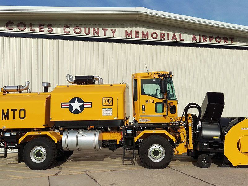 A yellow mto truck is parked in front of coles county memorial airport
