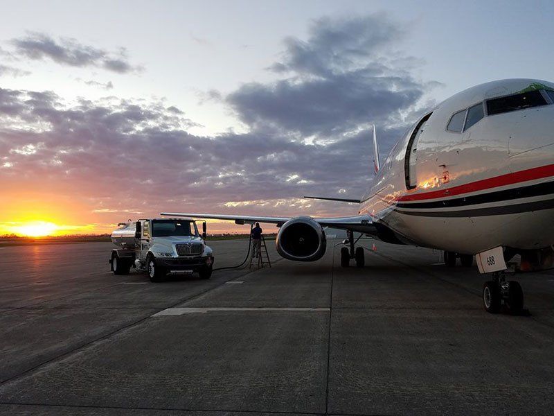 A plane is being refuelled on a runway at sunset