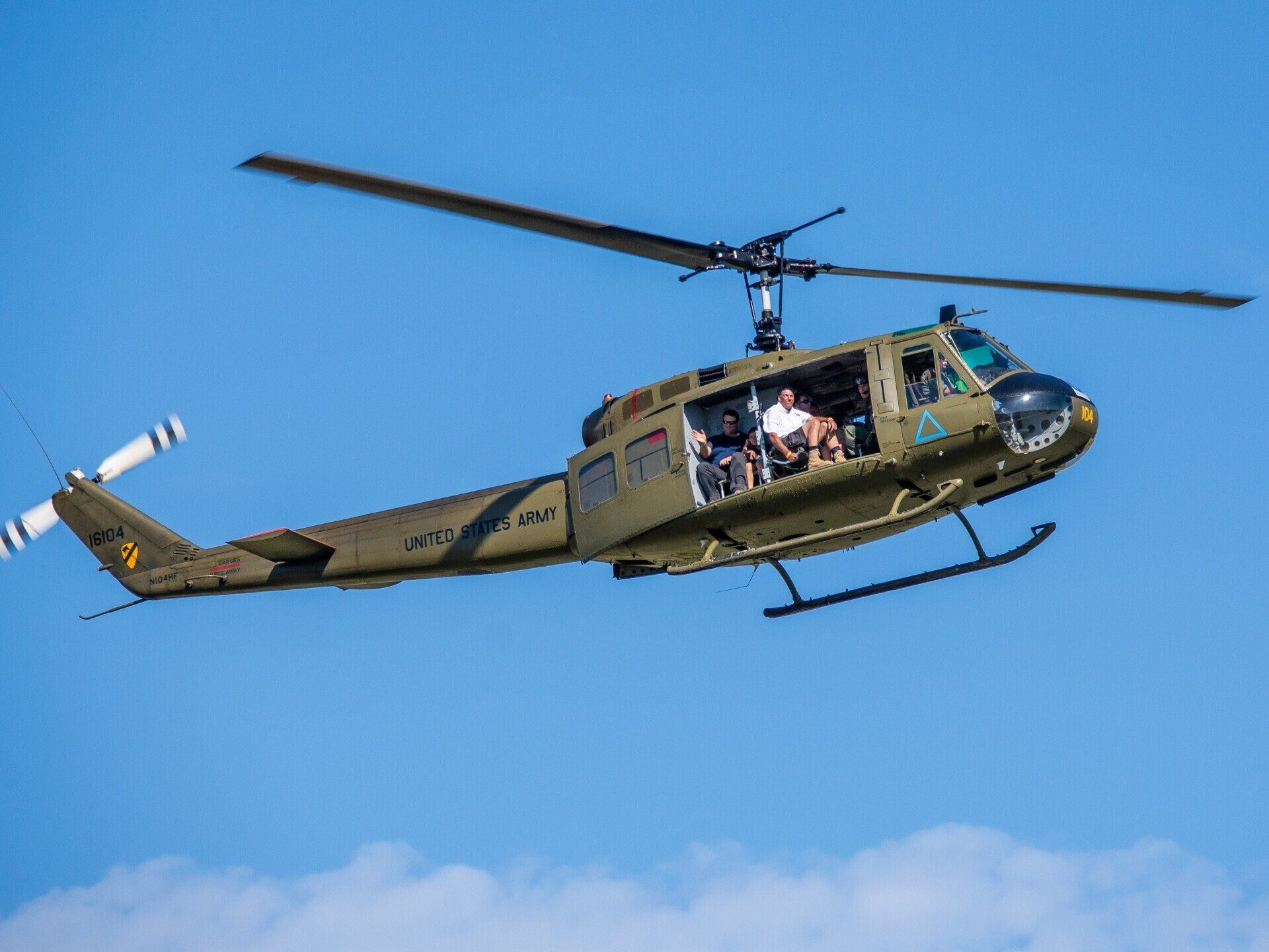 A military helicopter is flying through a blue sky.
