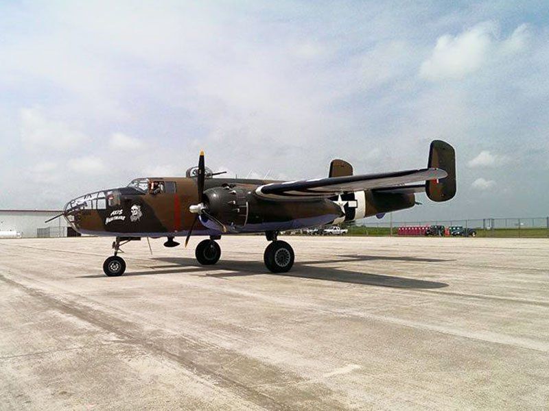 A military plane is parked on the tarmac at an airport