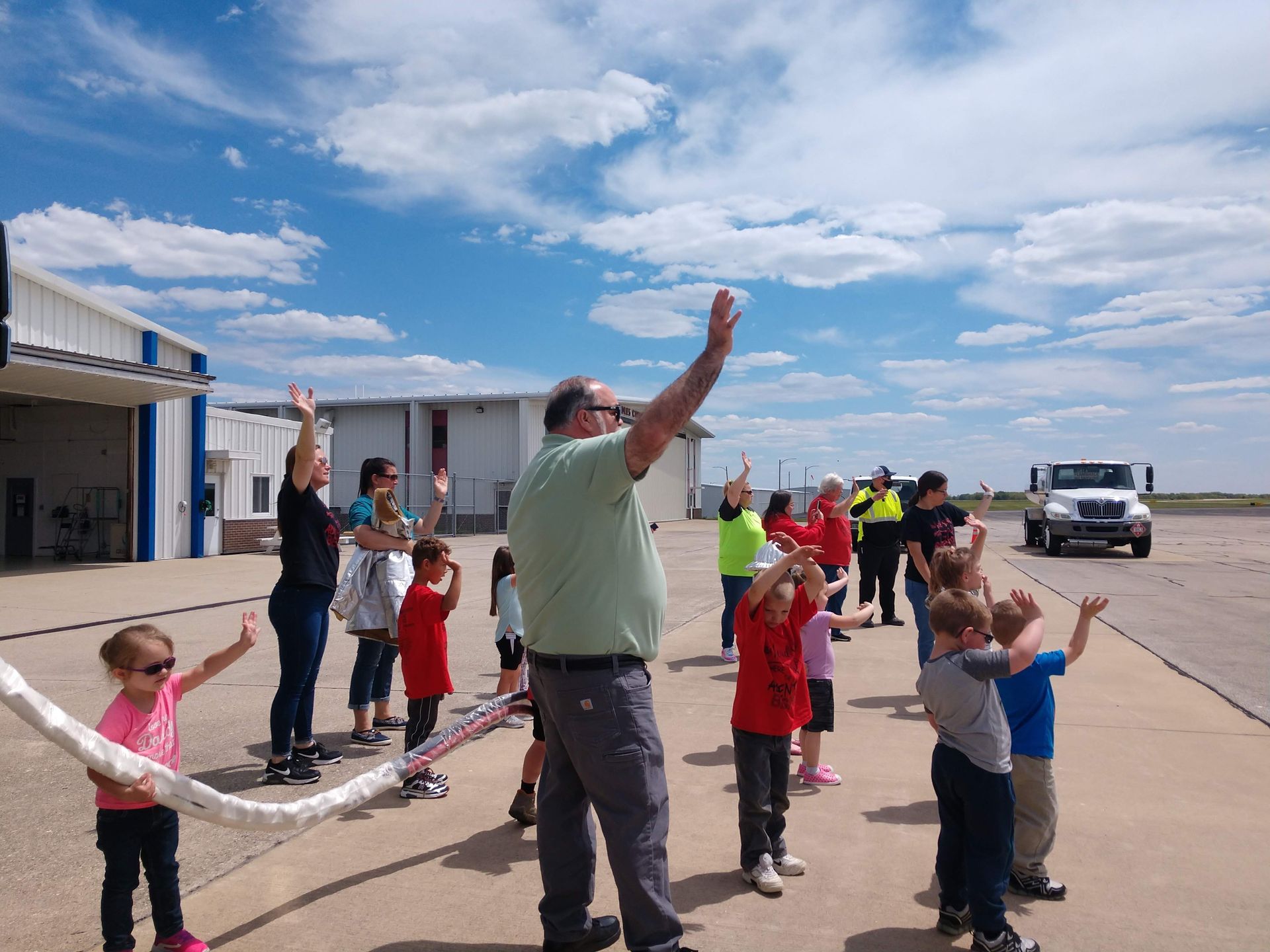 A group of people are standing on a runway with their arms in the air.