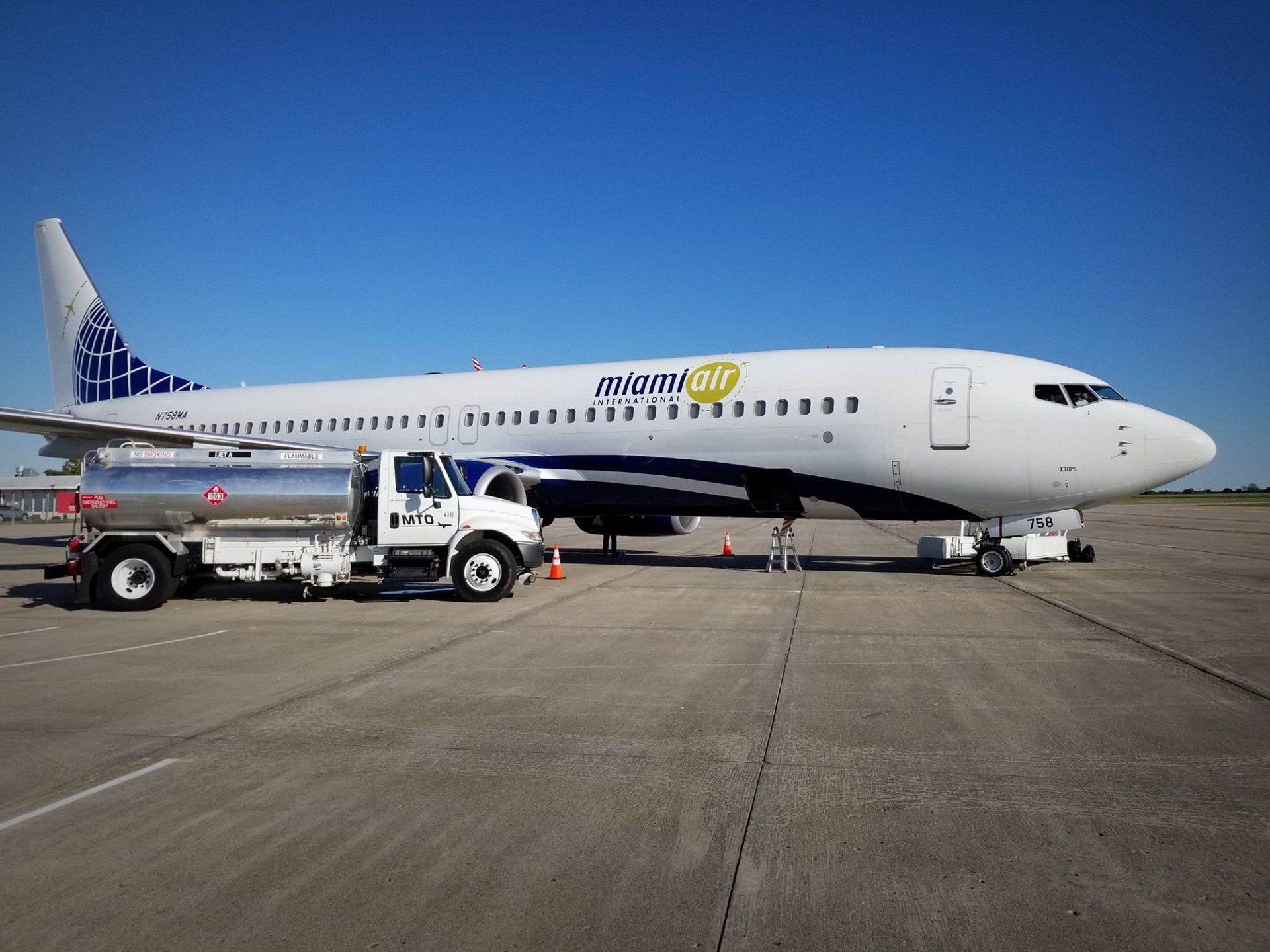 A plane is being fueled by a tanker truck