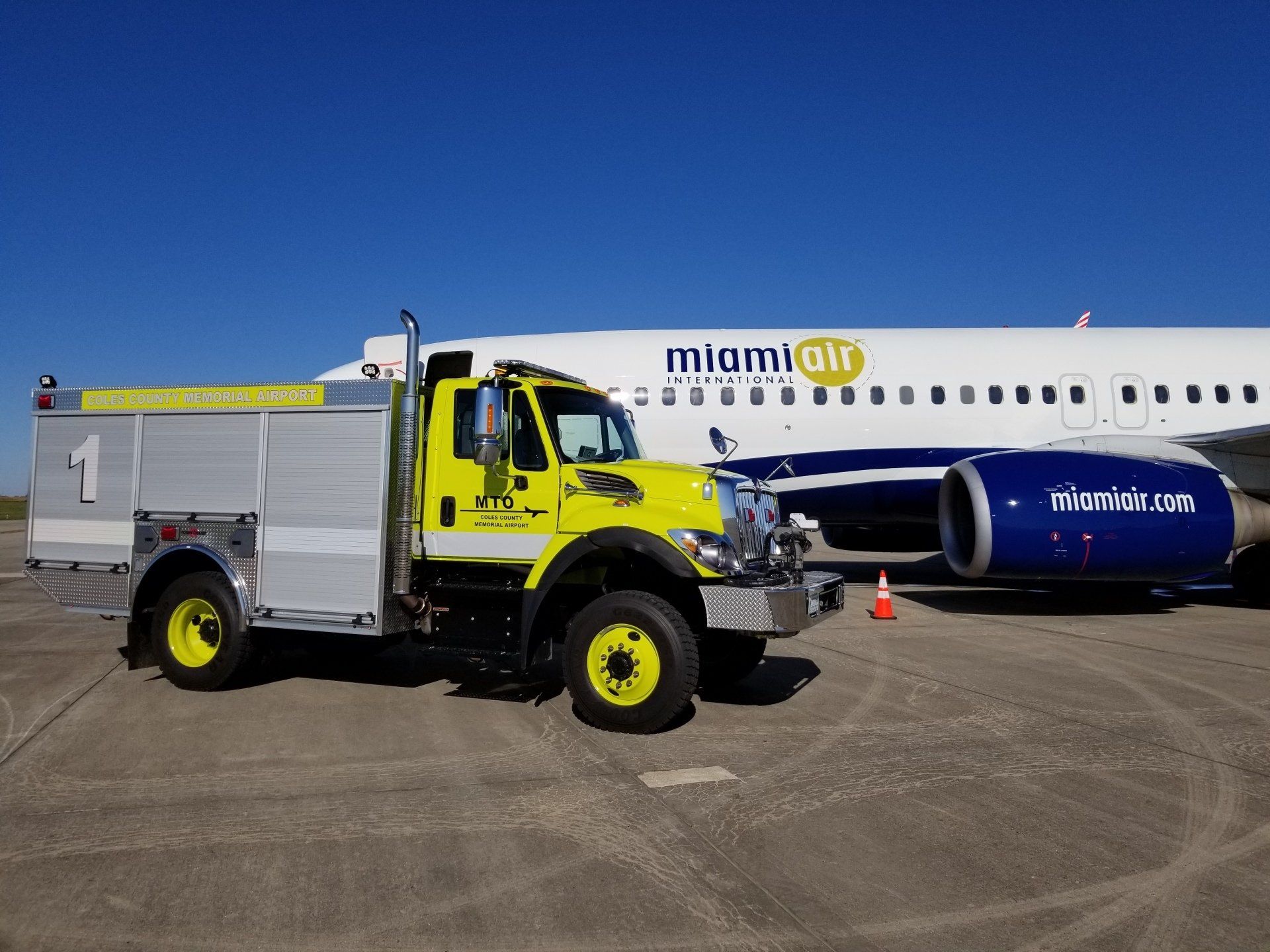 A miami air plane is parked next to a fire truck