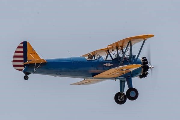 A blue and yellow propeller plane is flying in the sky