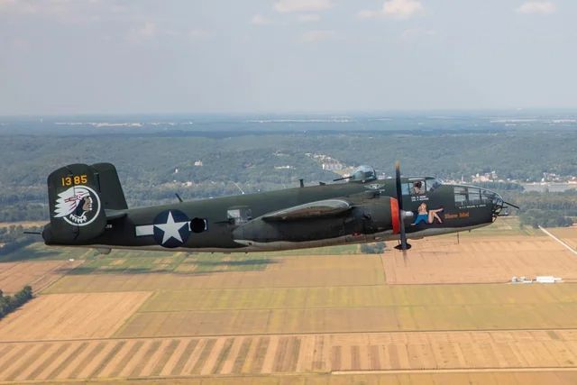 A large military plane is flying over a field