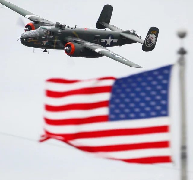 A plane is flying over an American flag