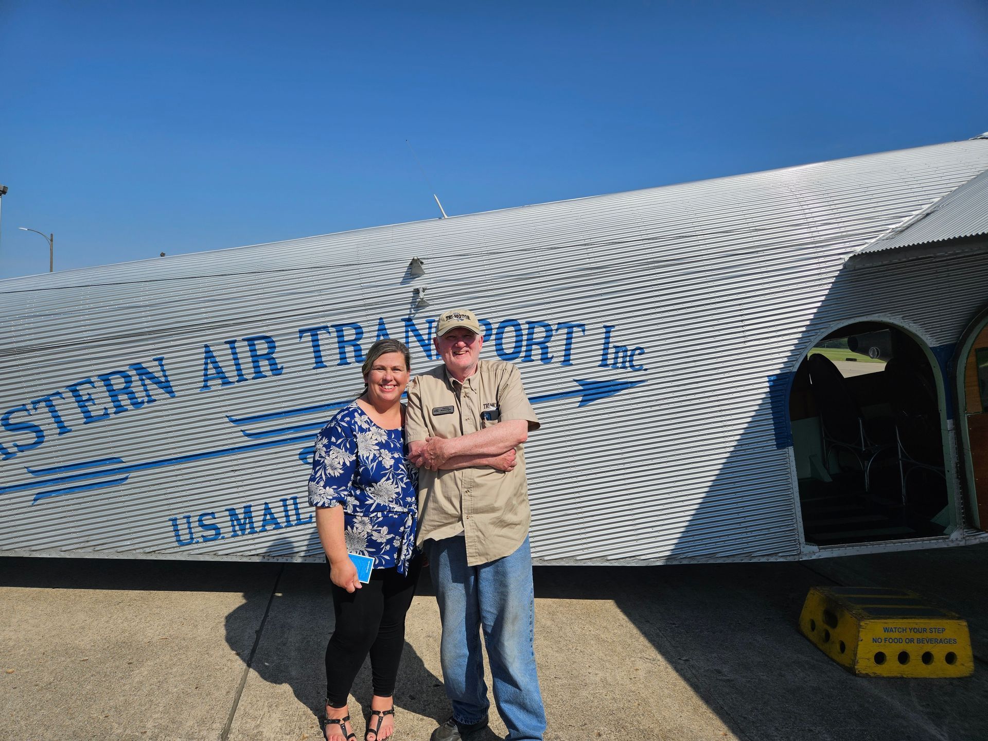 A man and woman standing in front of a stern air transport plane