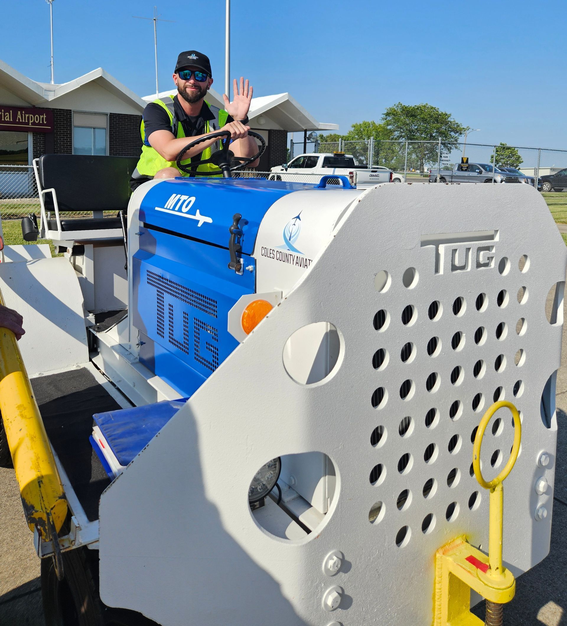 A man in a yellow vest is driving a tugboat