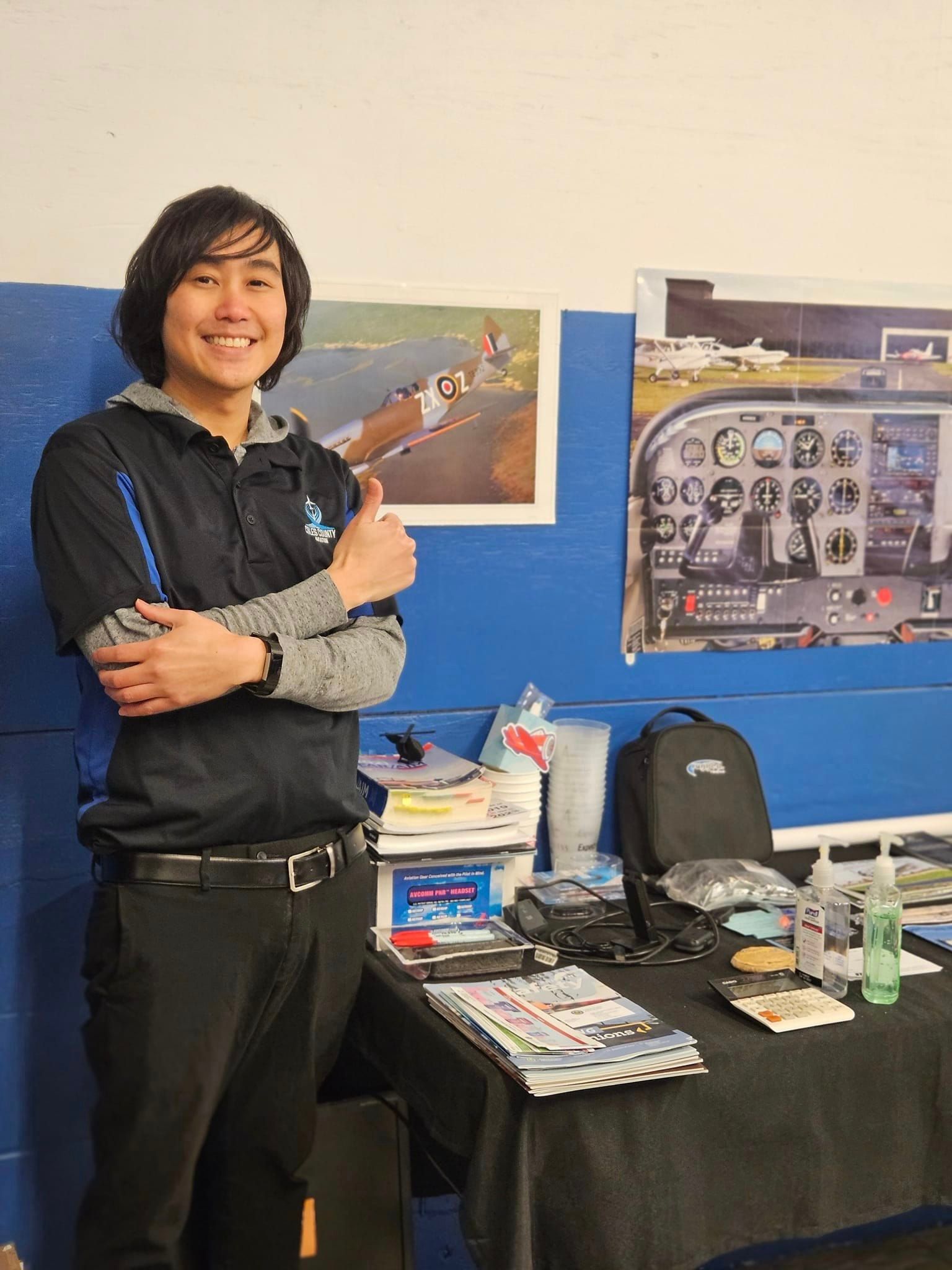 A man is giving a thumbs up while standing in front of a table.
