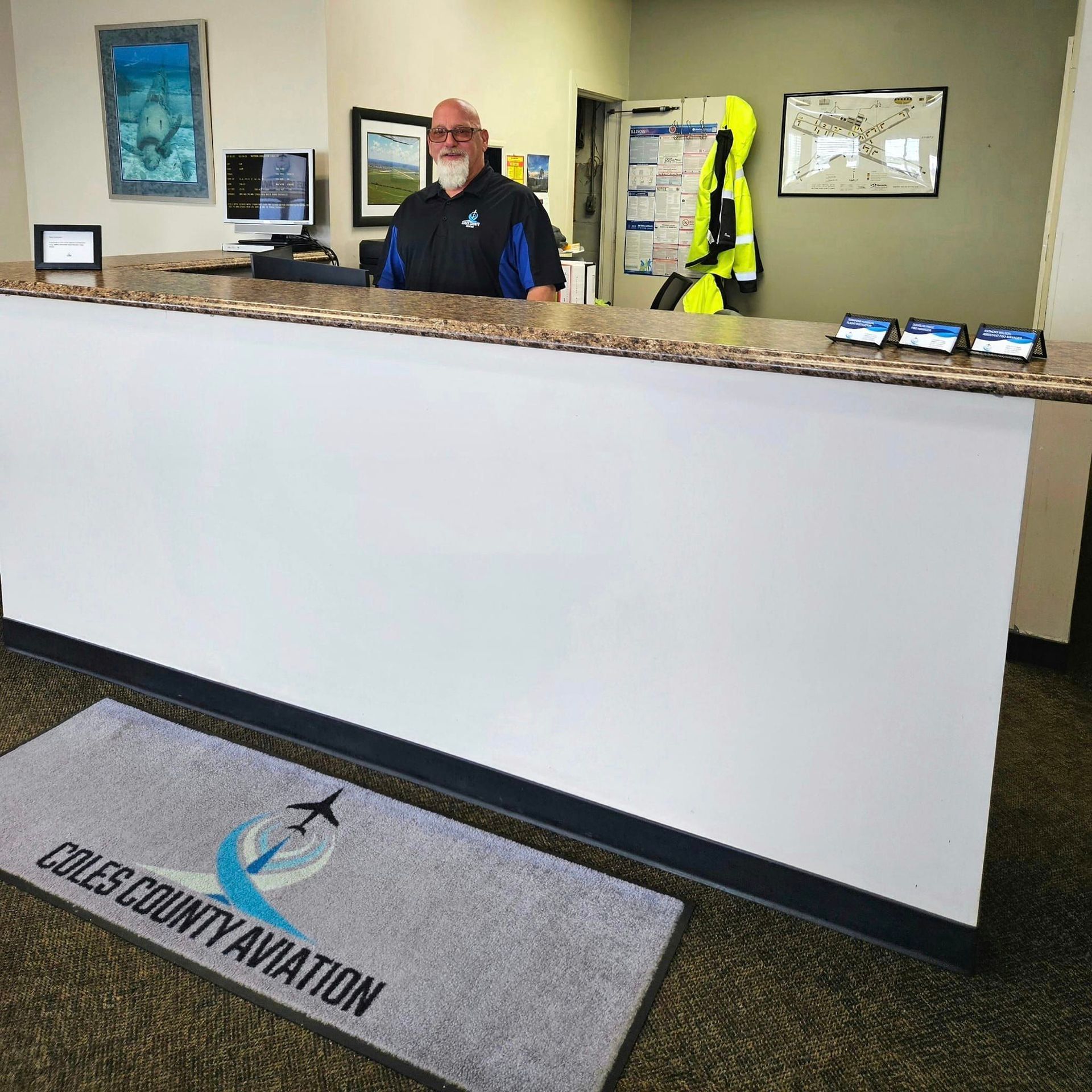 A man stands behind a counter that says ' valley county aviation ' on it