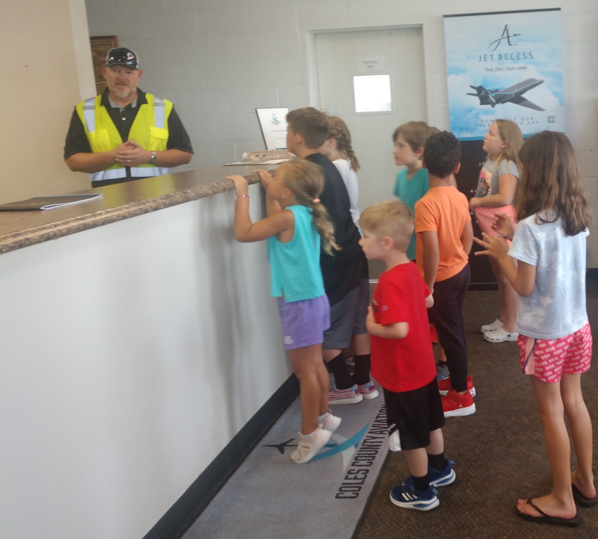 A group of children are standing in front of a counter with a sign that says a on it
