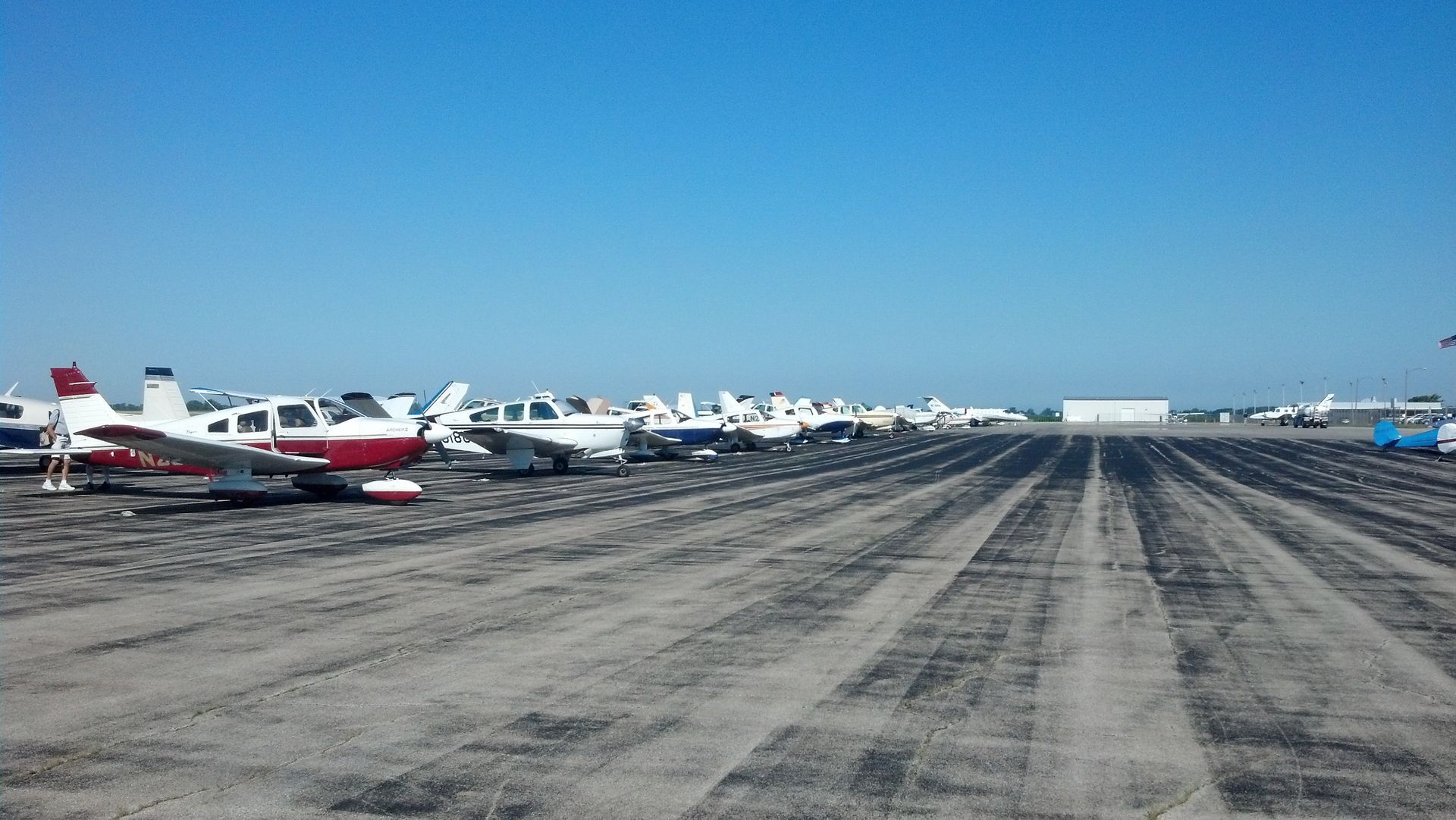 A row of small planes are parked on a runway.