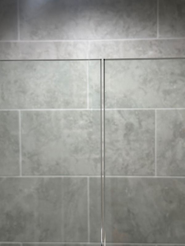 Gray tiled wall with a narrow vertical seam or door handle centered in the frame.