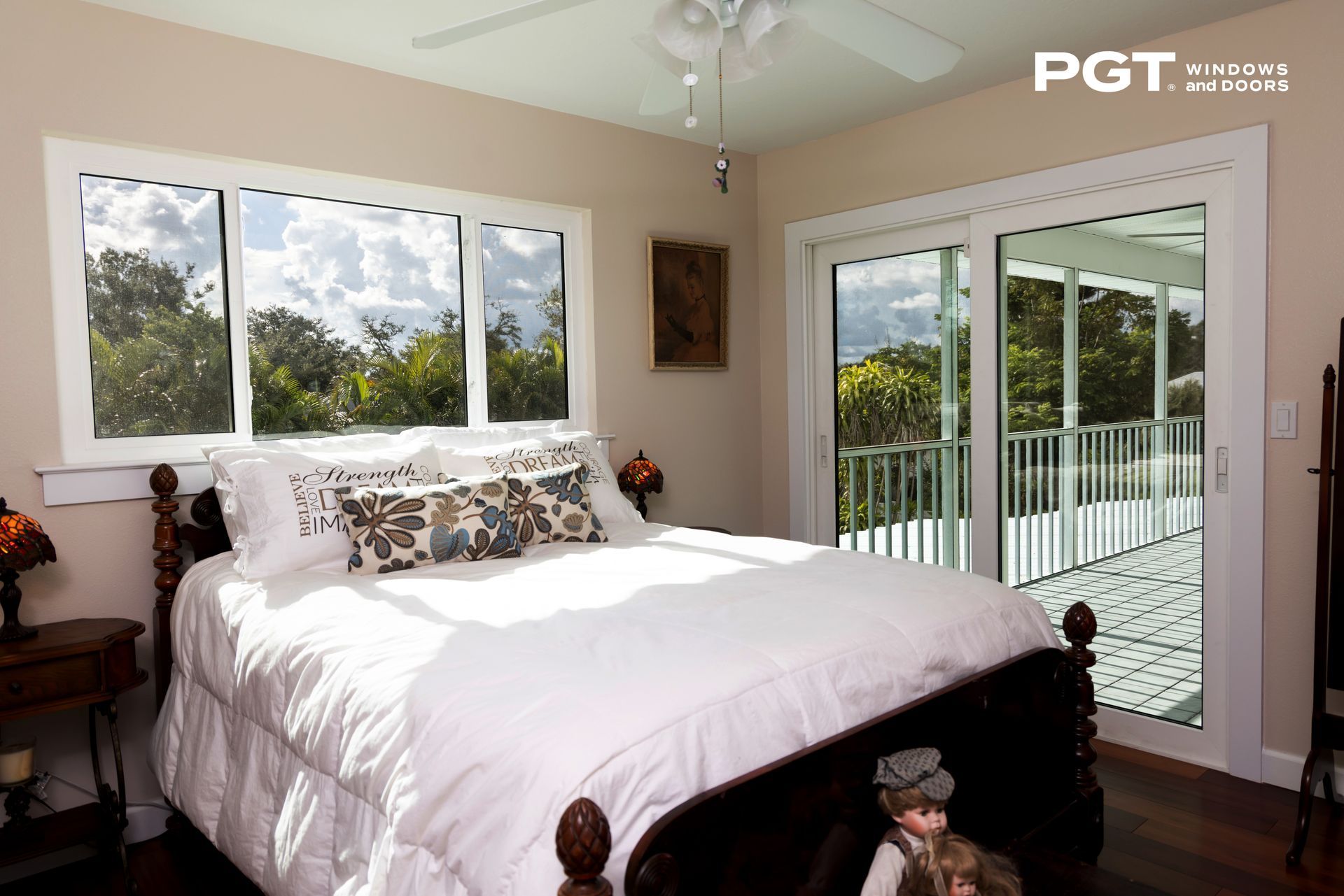 Bright bedroom with white bed, large windows, and sliding glass doors to a balcony.