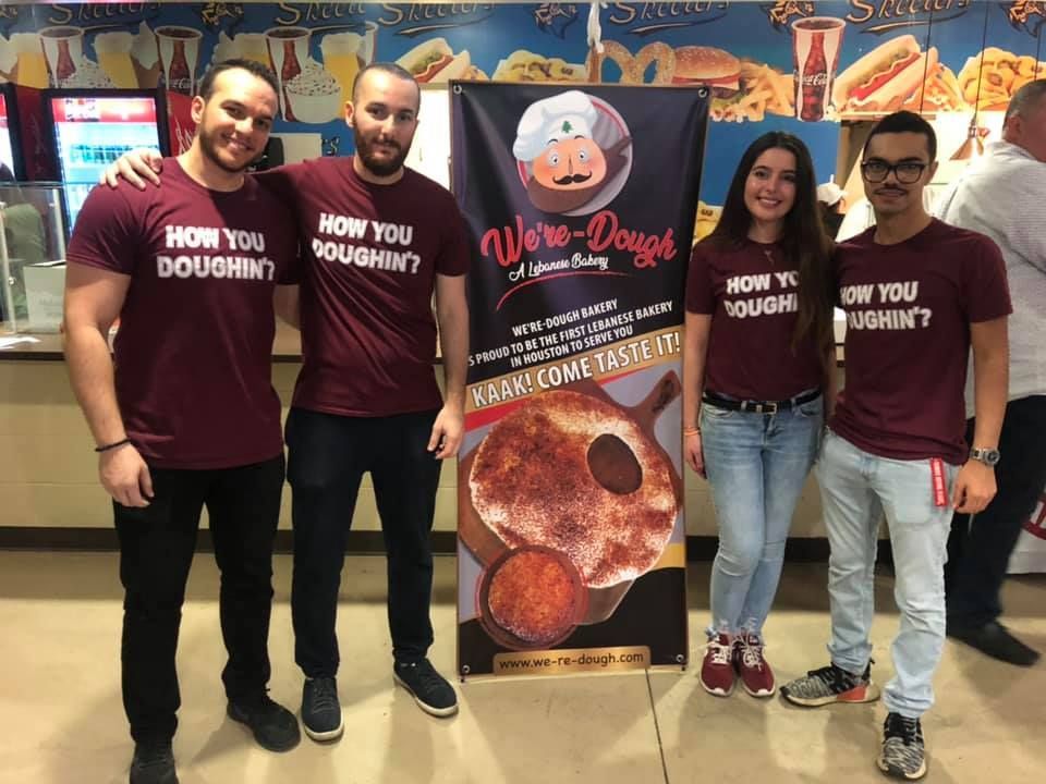 Four people wearing matching burgundy shirts pose next to a