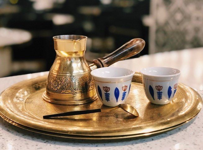 Golden coffee pot and cups on a brass tray, set for brewing Turkish coffee.