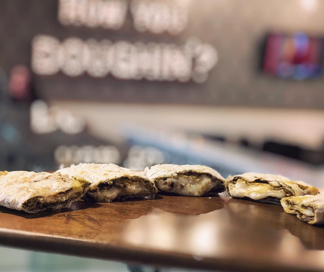 Close-up of pastries with filling on a wooden surface, with a blurred sign in background reading