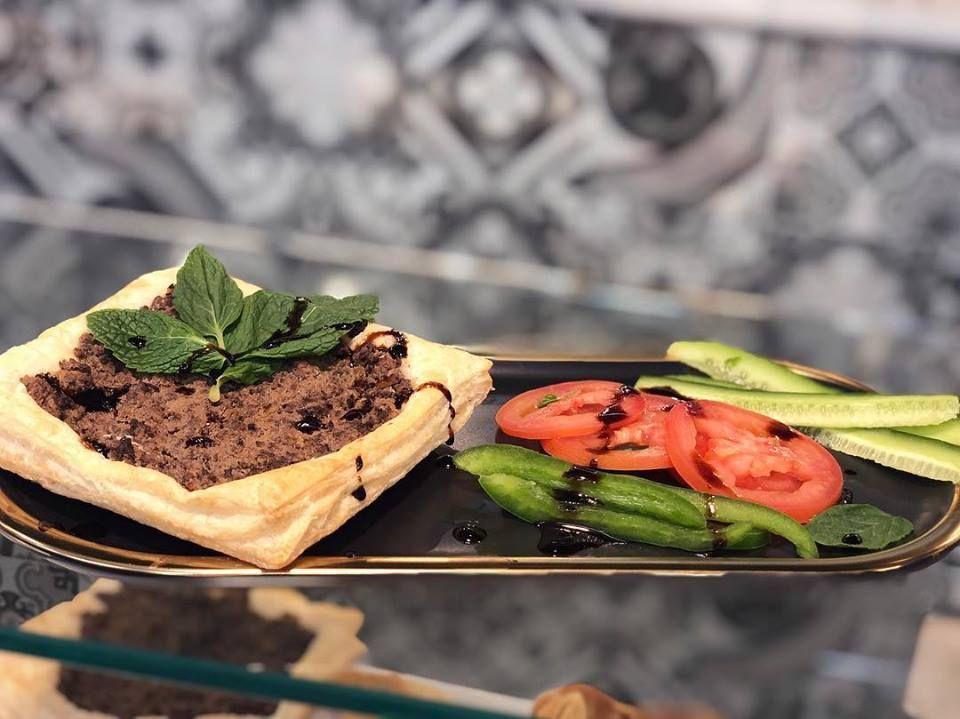 Savory pastry filled with meat, served with sliced tomatoes, cucumbers, peppers, and mint.