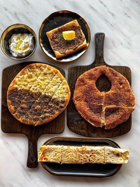 Assortment of Middle Eastern flatbreads and dip arranged on wooden boards; marble background.