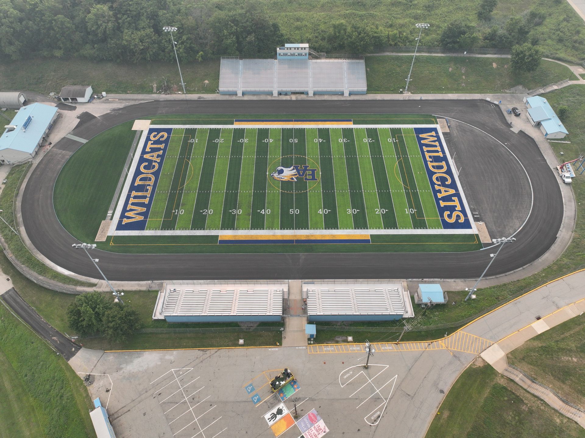 Aerial view of a football field in a stadium with blue end zones and bleachers at the bottom.