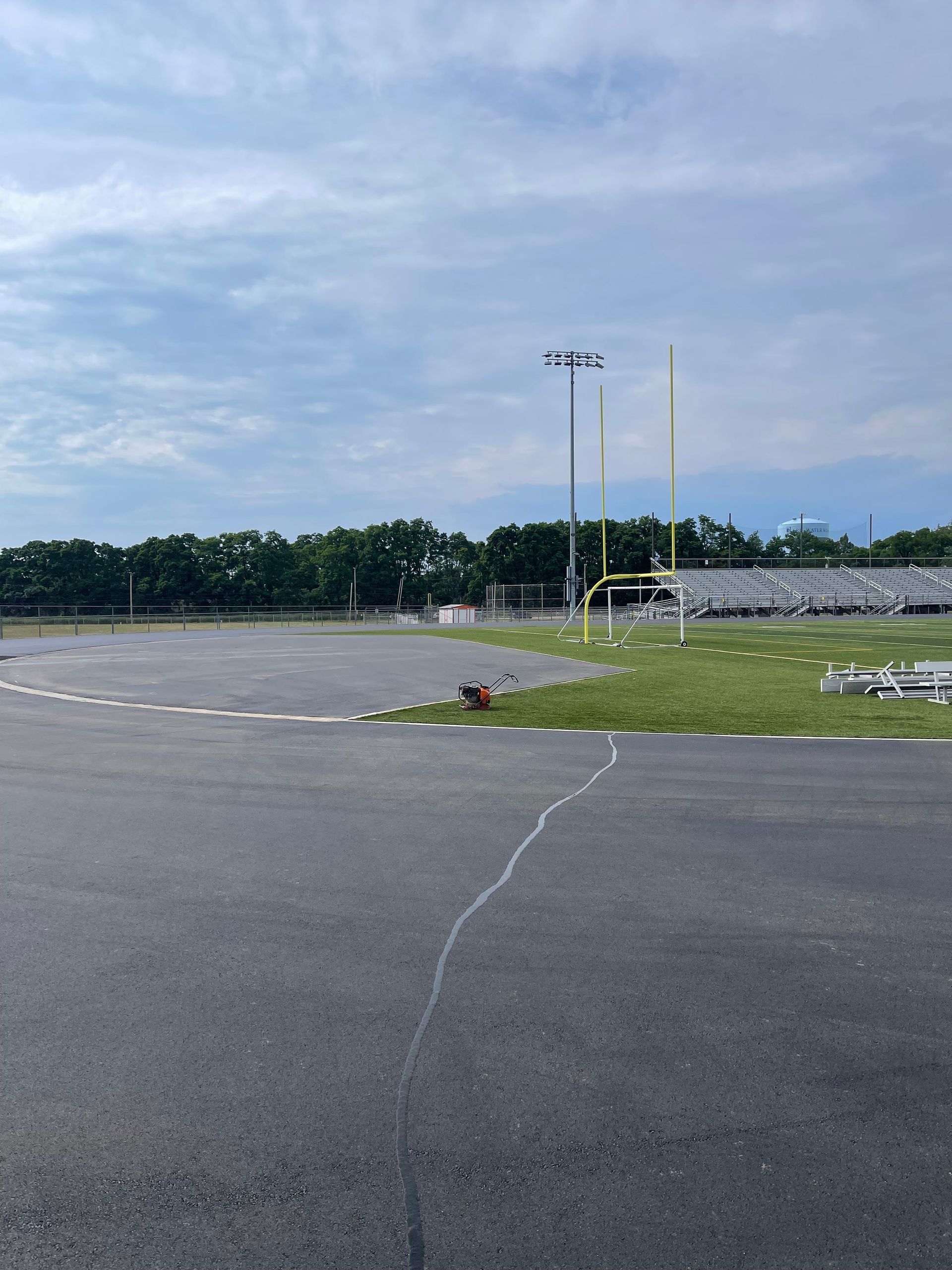 An empty parking lot with a football field in the background