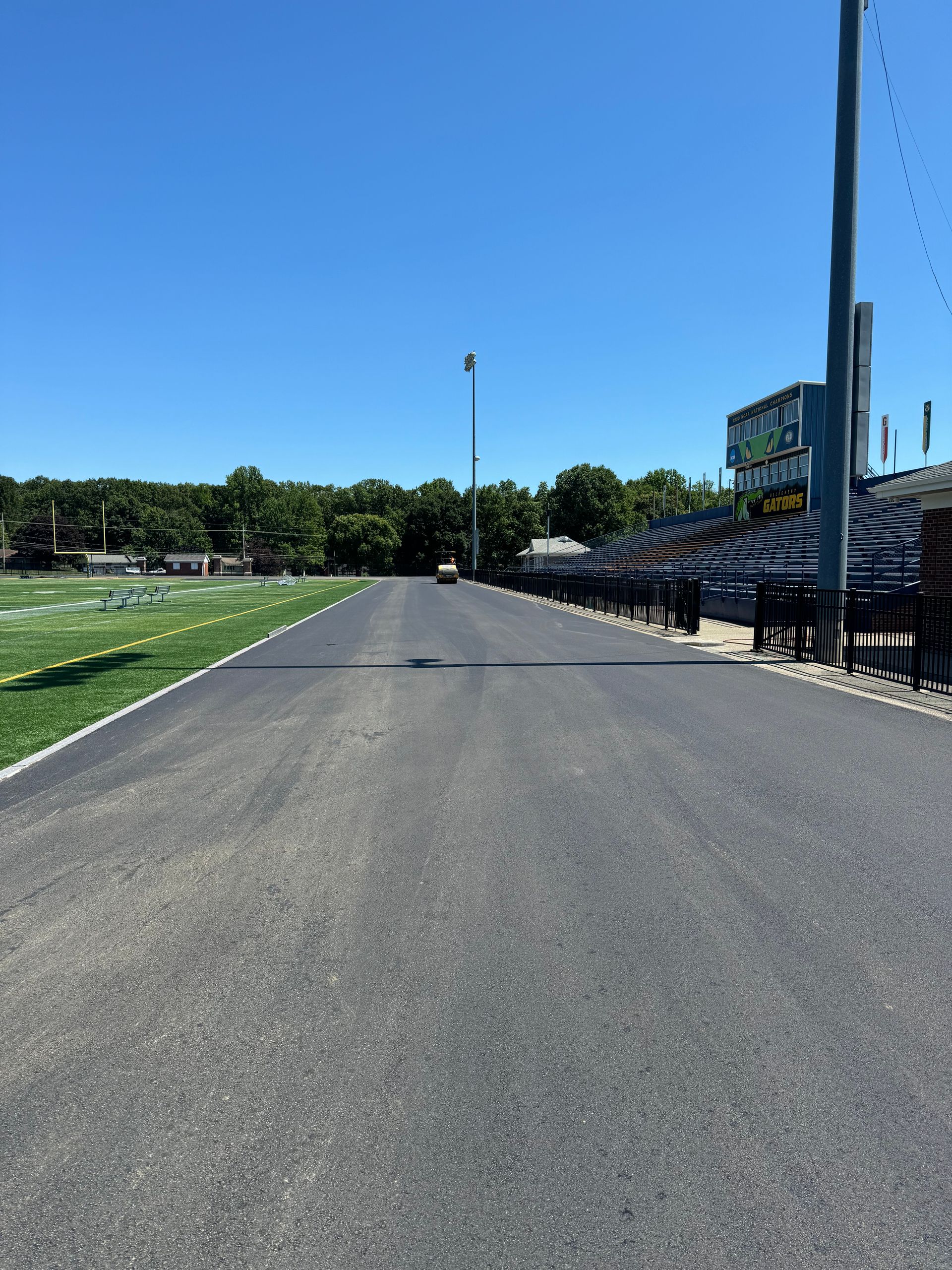 A road leading to a football field with a scoreboard in the background