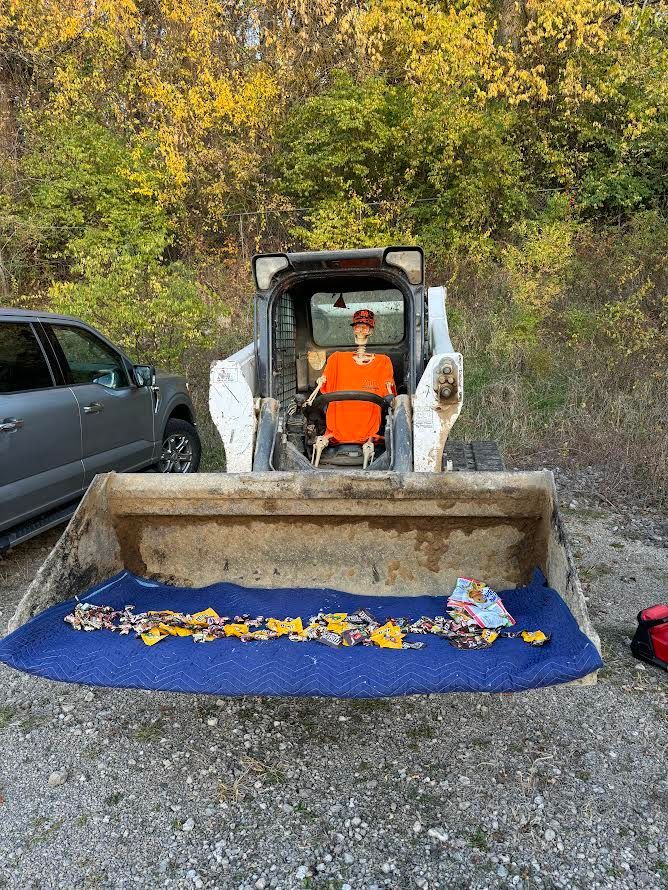 A bulldozer is parked in a gravel lot next to a car.