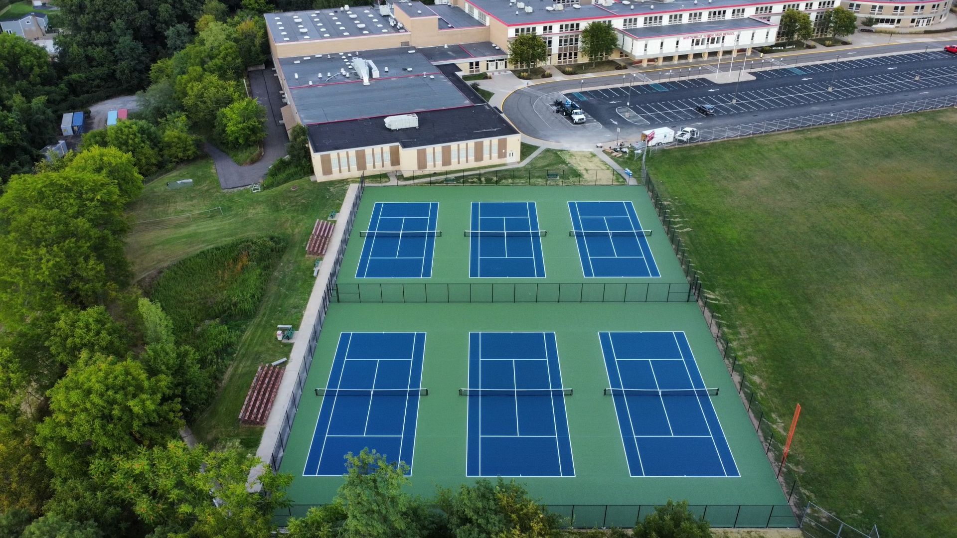 An aerial view of a tennis court with a building in the background.